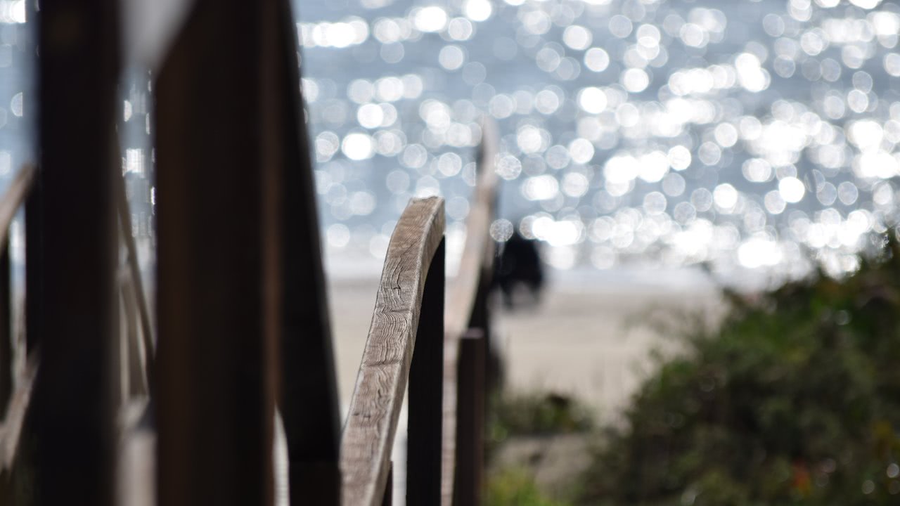 Holzgeländer am Strand mit ausgeprägtem Bokeh